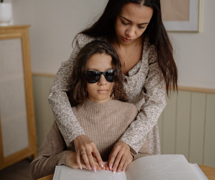 A woman teaching a little girl to read braille.